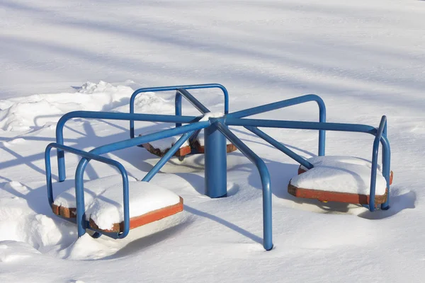 Carrossel de crianças que é enterrado na neve em uma ensolarada de inverno — Fotografia de Stock