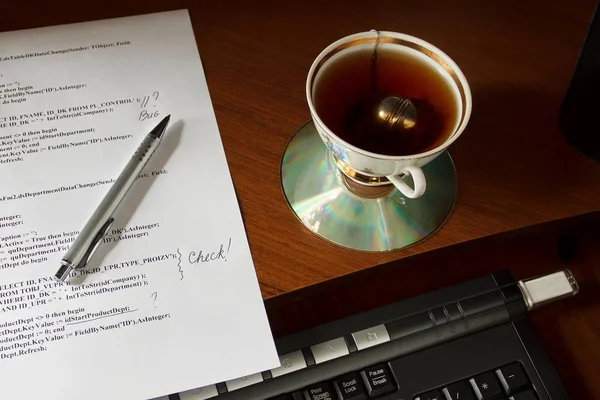 computer program listing with marks on the table near the cup of tea and keyboard