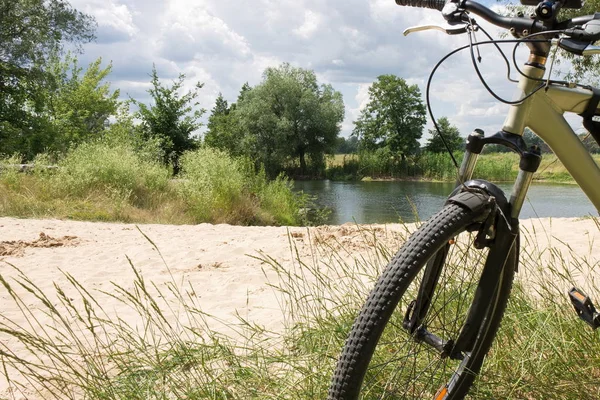 Sandy beach üzerinde nehir kıyısında bir yürüyüş sırasında ön planda bir bisiklet ile