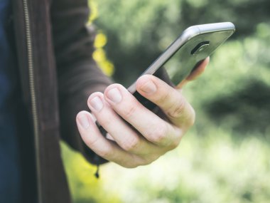 Holding ve parkta hareket eden smartphone kullanarak adamın elleri