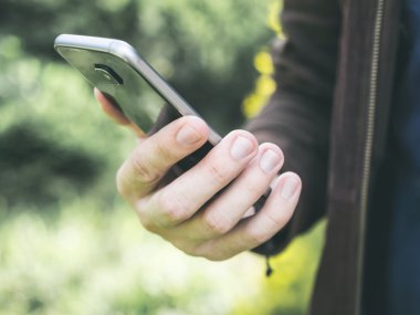 Holding ve parkta hareket eden smartphone kullanarak adamın elleri