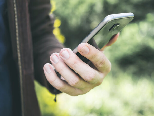 Мужские руки держат и используют мобильный смартфон в парке
