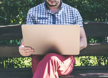 Genç adam oturan bir tezgah ve onun Laptop üzerinde çalışıyor