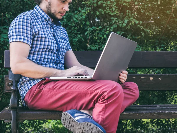 Bankta oturan onun dizüstü bilgisayarda çalışan adam