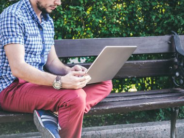 Bankta oturan onun dizüstü bilgisayarda çalışan adam