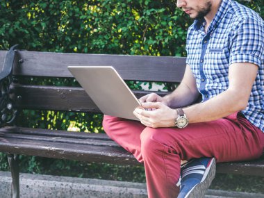 Genç adam parkta bankta oturmuş onun laptop çalışma
