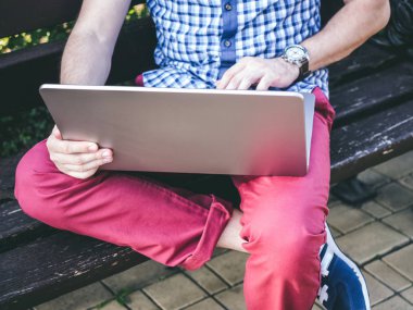 Bir genç adam parkta bankta oturmuş onun laptop üzerinde kapat