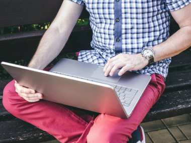 Genç adam oturan bir tezgah ve onun Laptop üzerinde çalışıyor