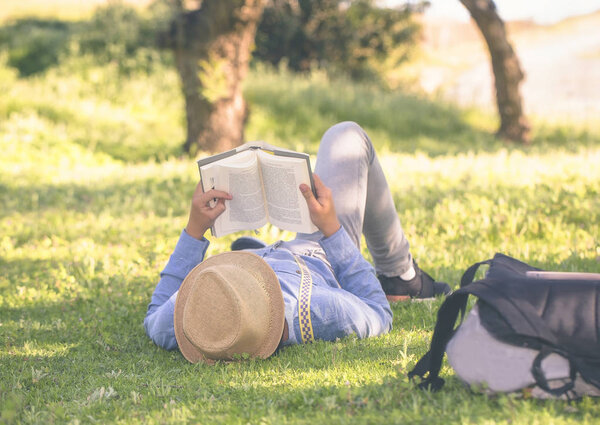 Молодой подросток спокойно читает на траве
