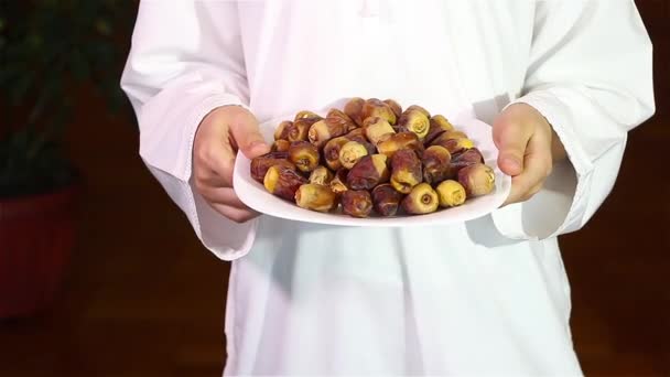 Pequeno garoto muçulmano apresentando um prato de tâmaras para iftar no Ramadã — Vídeo de Stock