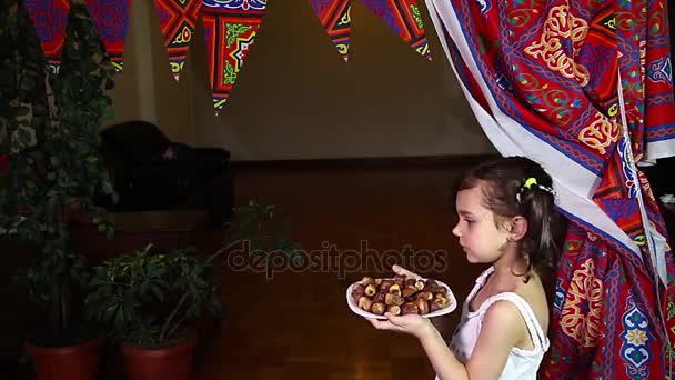 Little Muslim girl presenting a dish of dates for iftar in Ramadan — Stock Video