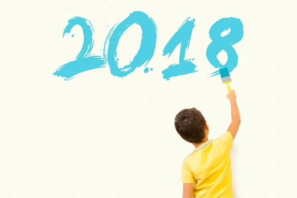 Симпатичний маленький хлопчик малює новий рік 2018 з пензлем на ходу — стокове фото