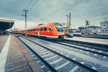 Railway station with beautiful modern red commuter train at suns