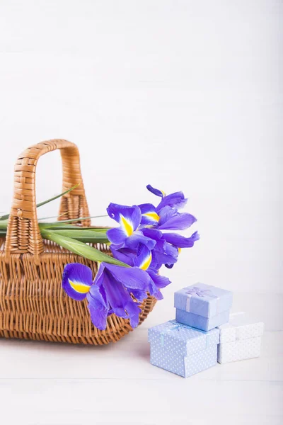 Bouquet d'iris dans le panier avec des boîtes-cadeaux sur fond en bois blanc — Photo
