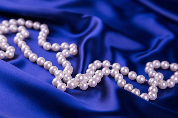 Perlový náhrdelník na tmavě modré saténové látky — Stock fotografie