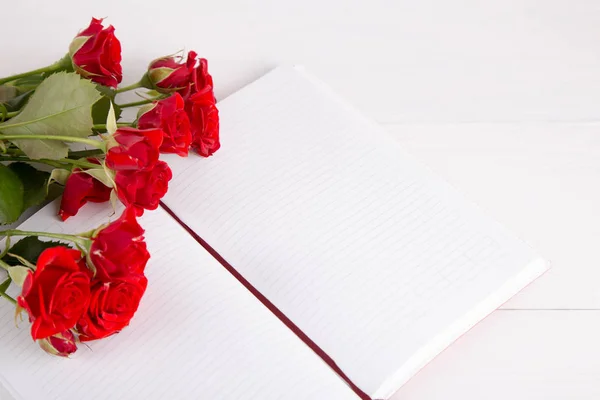 Buquê de rosas vermelhas com caderno aberto sobre fundo branco — Fotografia de Stock