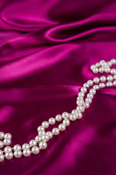 Collar de perlas en tela de satén carmesí curvado —  Fotos de Stock