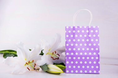 Lila alışveriş çantası üzerinde beyaz backgro beyaz lilyum buketi ile