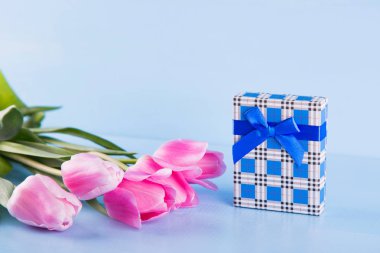 Mavi ahşap arka plan üzerinde hediye kutusu ile Pembe Lale buketi