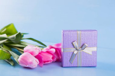 Mavi ahşap arka plan üzerinde hediye kutusu ile Pembe Lale buketi