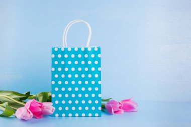 Mavi alışveriş çantası mavi ahşap bac üzerinde Pembe Lale buketi ile