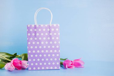 Lila alışveriş çantası mavi ahşap ba üzerinde Pembe Lale buketi ile