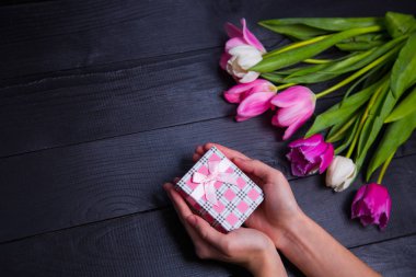 Hediyelik kutu elinde buket Pembe Laleler koyu ahşap bac üzerinde