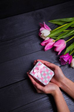 Hediyelik kutu elinde buket Pembe Laleler koyu ahşap bac üzerinde