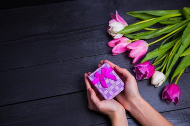 Hediyelik kutu elinde buket Pembe Laleler koyu ahşap bac üzerinde