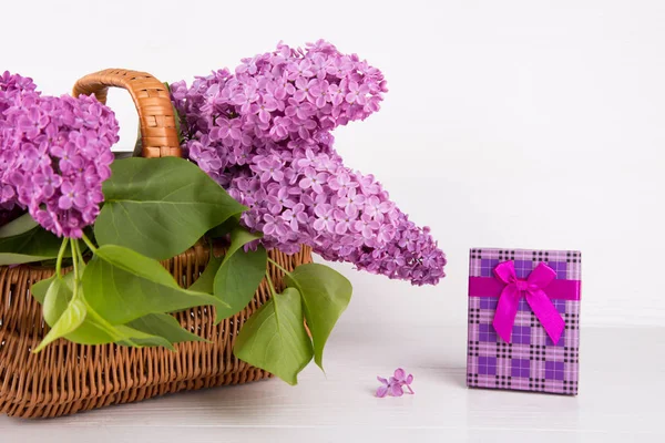 Bouquet de lilas dans un panier en osier avec boîte cadeau violet sur blanc — Photo