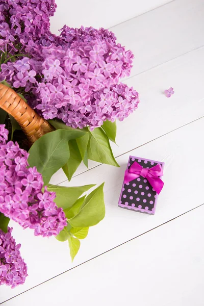 Bouquet de lilas dans un panier en osier avec boîte cadeau violet sur blanc — Photo