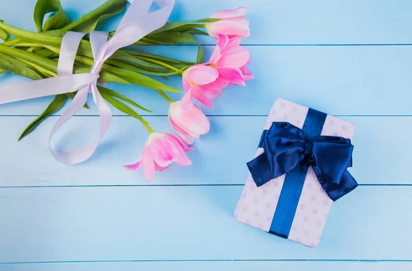 Ramo de tiernos tulipanes rosados con caja de regalo en respaldo de madera azul — Foto de Stock