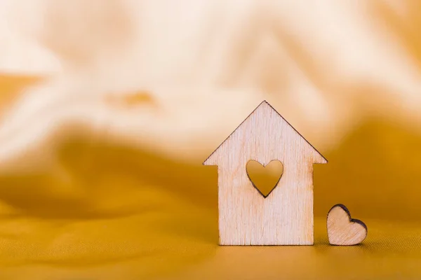 Wooden house with hole in form of heart on golden satin fabric — Stock Photo, Image
