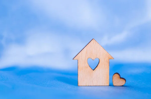 Wooden house with hole in form of heart on blue satin fabric — Stock Photo, Image