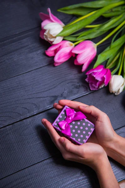 Hediyelik kutu elinde buket Pembe Laleler koyu ahşap bac üzerinde