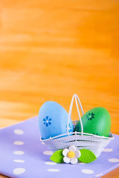 Bunte Ostereier im Korb mit Blume auf Stoff auf Holz — Stockfoto