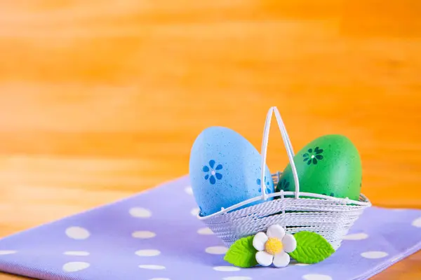 Huevos de Pascua coloridos en cesta con flor en tela en madera b — Foto de Stock