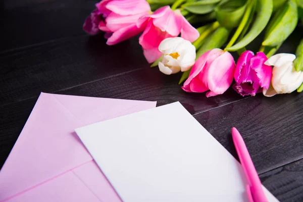 Ramo de tiernos tulipanes rosados y papel transparente sobre ba de madera negra — Foto de Stock