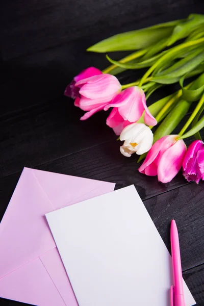Buquê de tulipas rosa macias e papel claro em ba de madeira preta — Fotografia de Stock