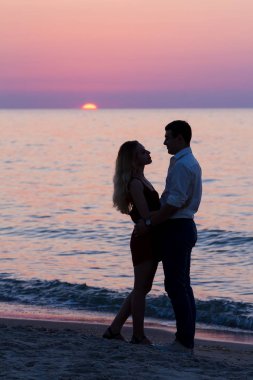 Deniz kenarında gündoğumu üzerinde genç çiftin karanlık siluetleri