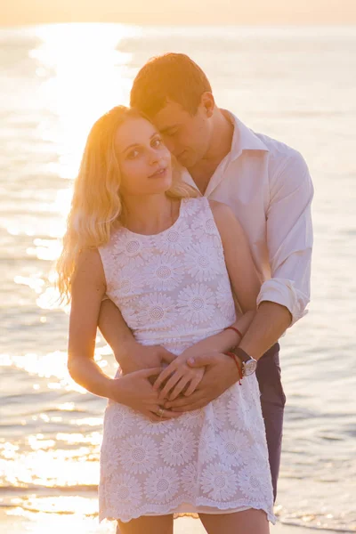 Joven pareja romántica a orillas del mar al amanecer dorado — Foto de Stock
