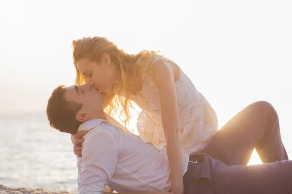 Pareja joven besándose en la playa al amanecer dorado — Foto de Stock