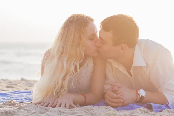 Pareja joven besándose en la playa al amanecer dorado — Foto de Stock