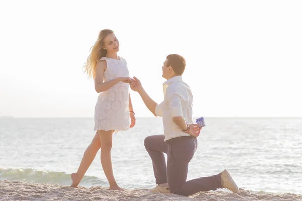 Joven pareja romántica a orillas del mar al amanecer dorado. El hombre propone — Foto de Stock