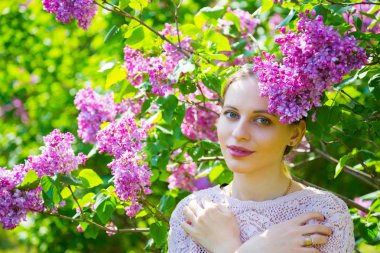 Güzel sarışın genç kadın çiçek açan arasında leylak ayakta bush