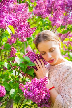 Güzel sarışın genç kadın çiçek açan arasında leylak ayakta bush