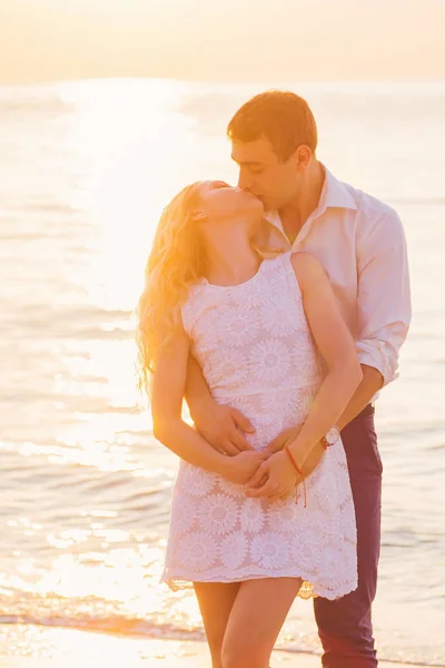 Hermosa pareja romántica joven besándose en la playa en rayos de ri — Foto de Stock