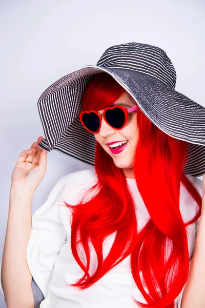 Atraktivní usměvavá rusovlasá mladá žena v sluneční brýle a čepice — Stock fotografie