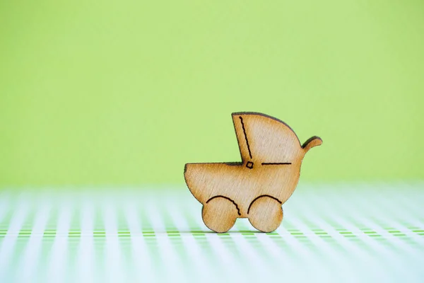 Wooden icon of baby buggy on green background — Stock Photo, Image