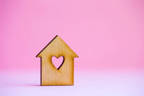 Casa de madeira com furo em forma de coração sobre fundo rosa — Fotografia de Stock